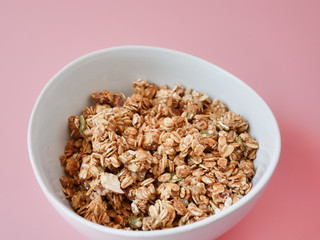 Cereal corn flake whole grains in white bowl on pink background.