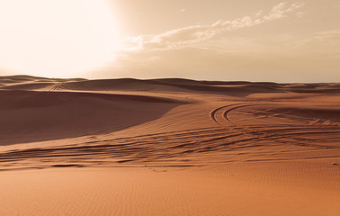 Sunset in the Dubai Desert with car marks in the sand