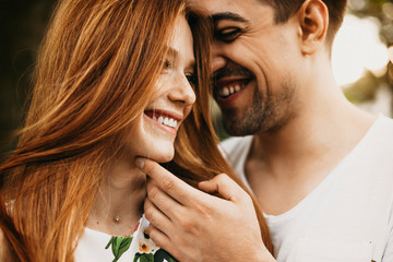 Close up portrait of a beautiful young caucasian couple having fun smiling while man is touching his girlfriends face while she is looking away smiling.