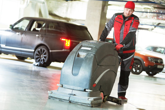 Worker With Machine Cleaning Floor In Parking Garage.