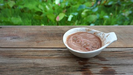 Melted chocolate ice cream in white bowl on wooden tabl
