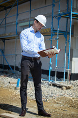 Architect inspects construction outside talking on the phone.