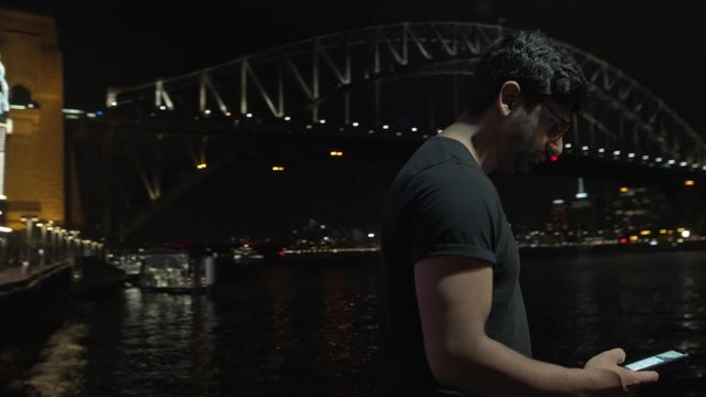 Man Looks at phone, Sydney Night Skyline, Theme Park and Harbour Bridge Behind