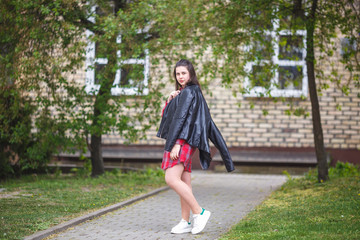 close up portrait of big plus size beautiful stylish kid girl with leather jacket  and red plaid shirt near brick building in urban street as background