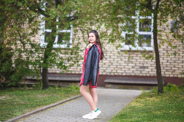 close up portrait of big plus size beautiful stylish kid girl with leather jacket  and red plaid shirt near brick building in urban street as background