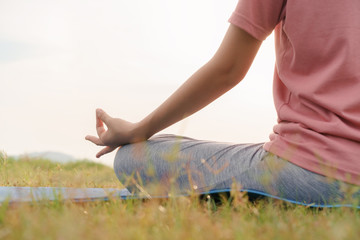close up hand and half body of health woman sit in lotus yoga position in the morning at park. Practicing yoga makes meditation for healthy breathing  and relaxation