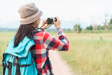 Asian tourist woman taking photo by digital camera on nature mountain view. A young girl is traveling on summer vacation.