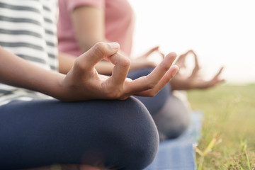 close up hand and half body of health woman sit in lotus yoga position in the morning at park. Practicing yoga makes meditation for healthy breathing  and relaxation