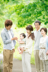 新緑の中で微笑む3世代家族