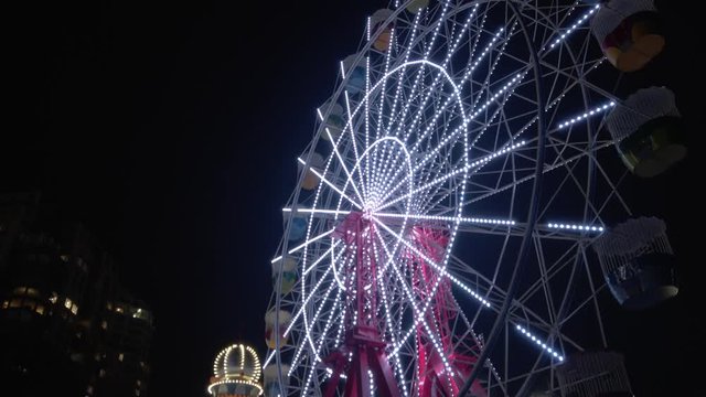 Camera Tilts Down on Ferris Wheel in Theme Park Revealing Other Buildings