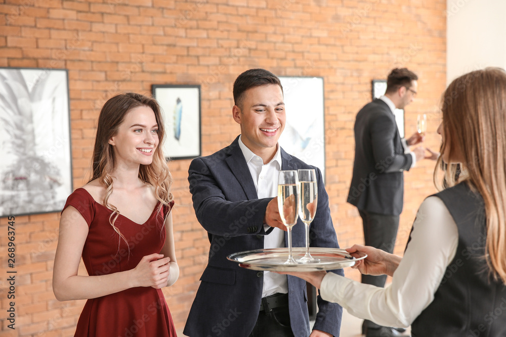 Wall mural Waiter suggesting champagne to visitors of modern art gallery