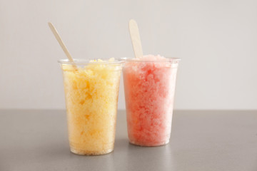 Cups with tasty shaved ice on grey table