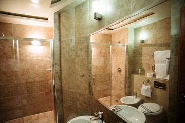 Bathroom in the apartment with brown marble tiles with bath, toilet and wash basin