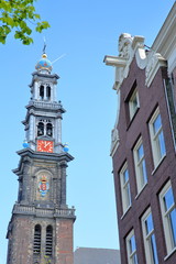 Close-up on the clock tower of Westerkerk church in Jordaan, Amsterdam, Netherlands, with a traditional heritage building in the foreground