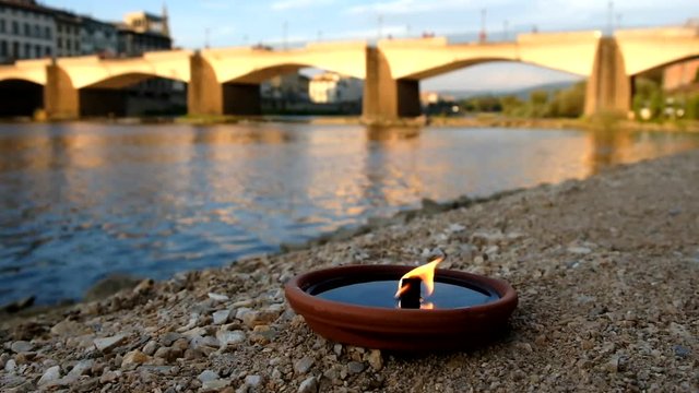 Florence, Italy. Oltrarno Easy Living area - circa May 2017 - Static shot of candle burning in front of the river and the bridge in Florence Italy, golden hour