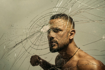 Determination to succeed. Muscular man having inner determination and commitment to break glass wall. Determined latino man removing obstacle with determination and confidence. Determination concept - obrazy, fototapety, plakaty