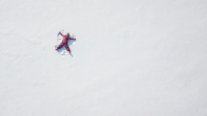 Kid making a snow angel. High point of view. Overhead view