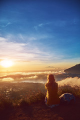 Woman enjoying nice landscape and sunrise from a top of mountain Batur, Bali, Indonesia.