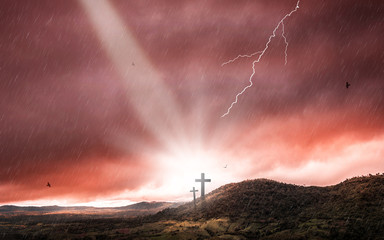 Silhouette of crucifix cross at sunset time with holy light and thunderstorm background.