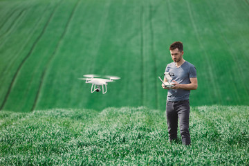Young man piloting a drone on a spring field - 268970109