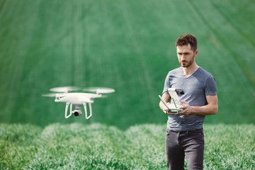 Young man piloting a drone on a spring field - 268970110