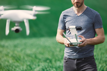 Young man piloting a drone on a spring field - 268970138