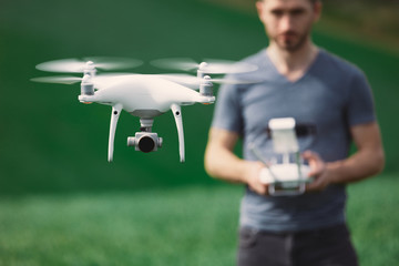 Young man piloting a drone on a spring field - 268970180