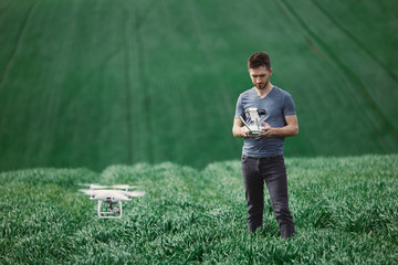 Young man piloting a drone on a spring field - 268970304