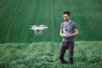 Young man piloting a drone on a spring field - 268970307