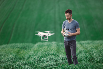 Young man piloting a drone on a spring field - 268970342
