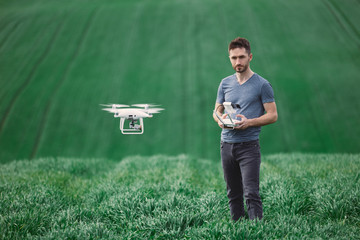 Young man piloting a drone on a spring field - 268970344