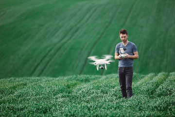 Young man piloting a drone on a spring field - 268970381