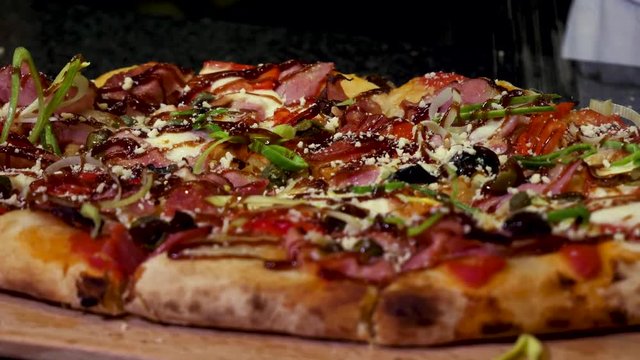 Close up for hands sprinkling delicious pizza with parmesan cheese, italian food concept. Frame. Chef hands putting cheese on freshly baked homemade pizza.
