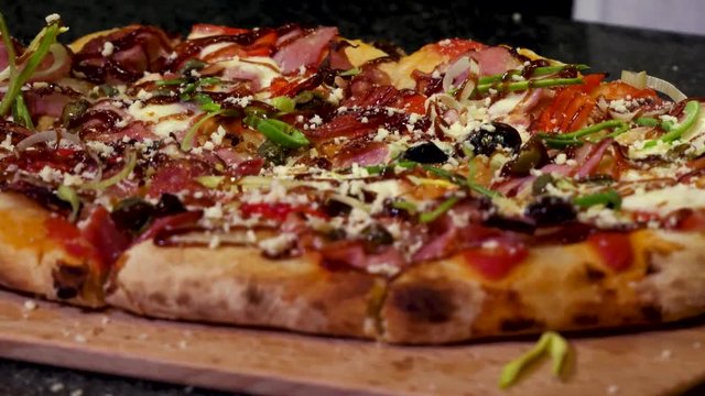 Close up for hands sprinkling delicious pizza with parmesan cheese, italian food concept. Frame. Chef hands putting cheese on freshly baked homemade pizza.