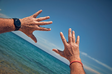 Man playing with his hands on a sandy tropical beach.