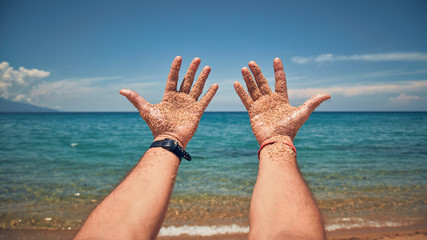 Man playing with his hands on a sandy tropical beach.