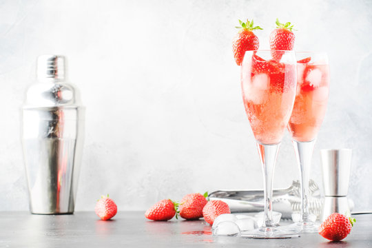 Rossini alcoholic cocktail with Italian sparkling wine, strawberry puree and ice in champagne glasses, place for text, selective focus