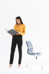 Full length portrait of caucasian young businesswoman dressed in elegant wear holding paper folder...