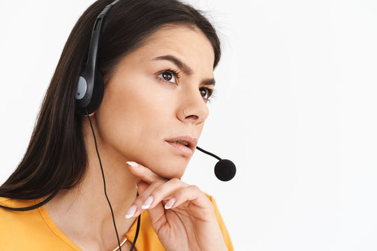 Photo of serious phone operator woman wearing microphone headset sitting in office and speaking with client