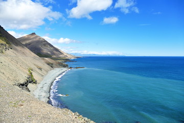 Fototapeta na wymiar View of Iceland's intense blue sea water and shoreline in bright sunlight