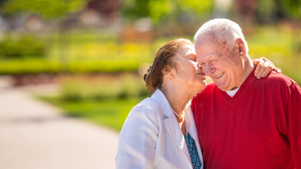 Cheerful senior couple having good time in city park, walking, laughing and enjoying sunny day