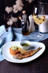 grilled fish with vegetables and lemon on the background of a glass of white wine