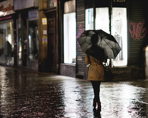 Walking in the city street under the rain with umbrella
