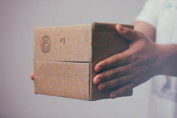 Delivery man with cardboard parcel. Hand holding the delivery box.