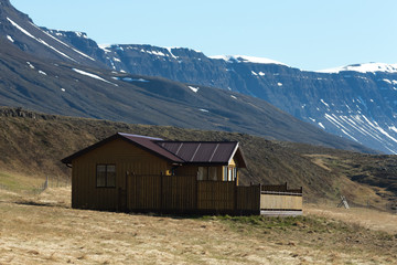 Fototapeta na wymiar Small house and snowy mountains in the fjord of Iceland