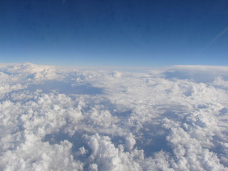Fototapeta na wymiar Panorama of an infinite snow-white cloudy field on the background of sky blue on the horizon, opens from the window of the plane.