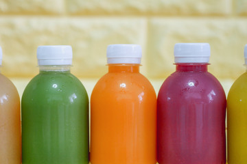 The bottles of cold pressed fruit and vegetables juice with yellow background.