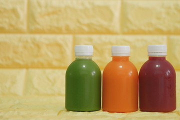 The bottles of cold pressed fruit and vegetables juice with yellow background.