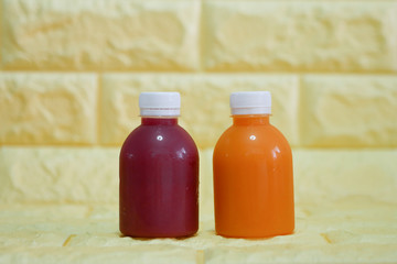 The bottles of cold pressed fruit and vegetables juice with yellow background.
