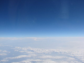 Panorama of an infinite snow-white cloudy field on the background of sky blue on the horizon, opens from the window of the plane.
